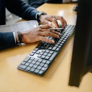 Close-up of hands typing on keyboard in an office setting, showcasing work professionalism.