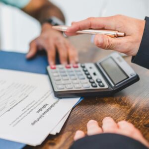 Hands working with a calculator and documents at a business meeting.